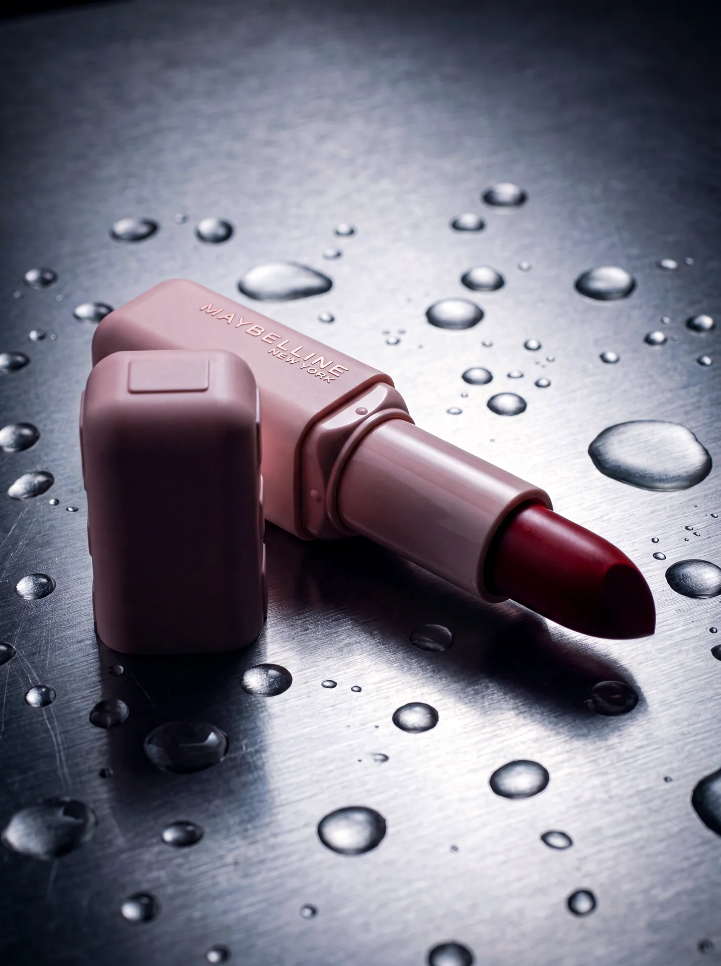 Close product still life with a lipstick object on wet reflective metal