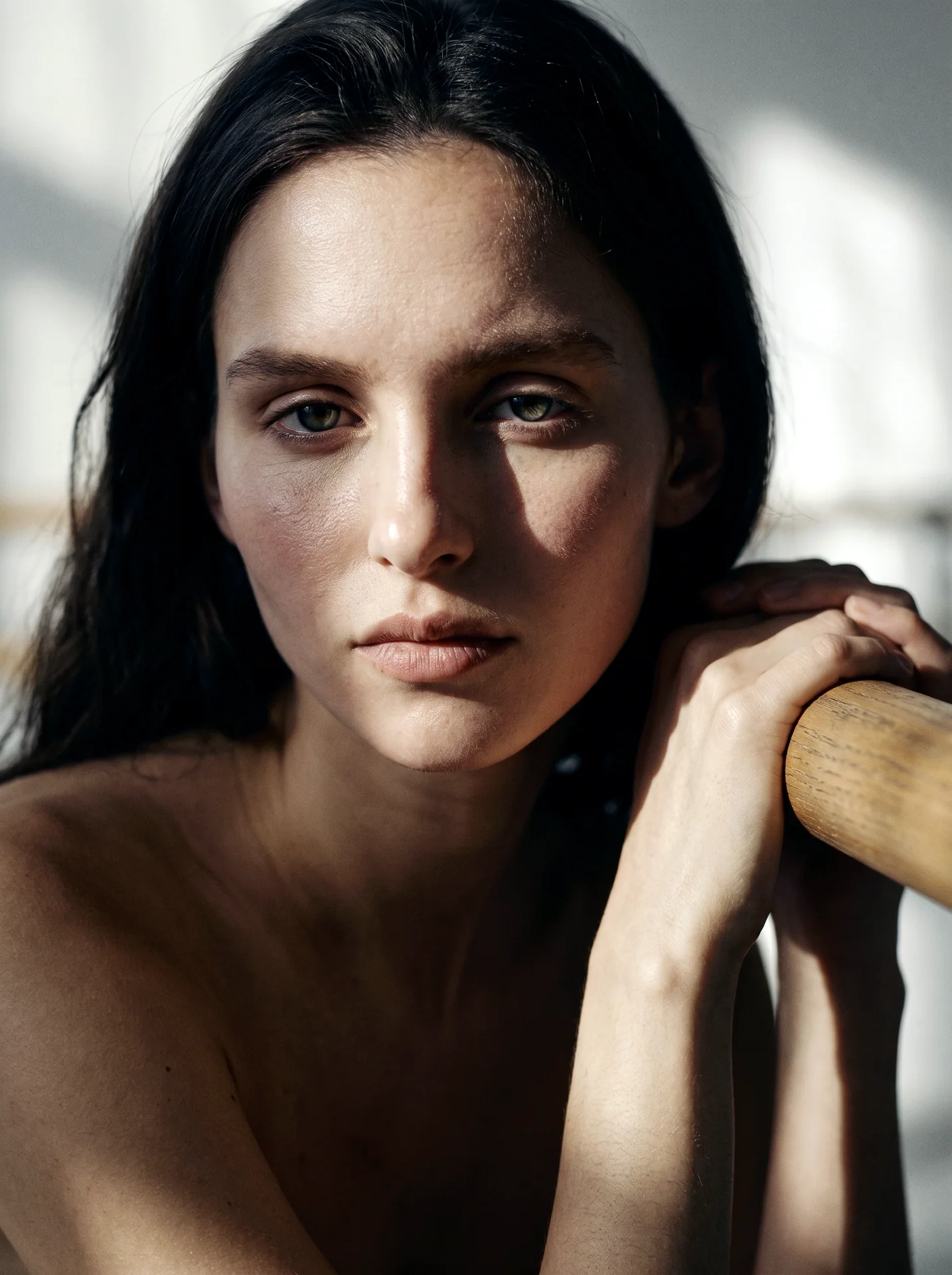 Close portrait of a dancer resting her hands on a ballet barre in strong window light